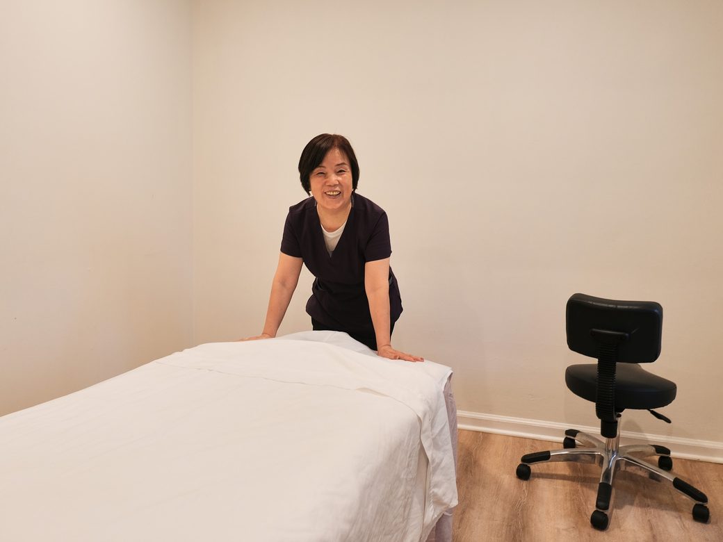 A practitioner beside a made-up treatment table at the clinic